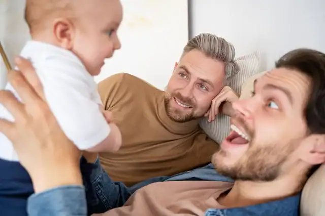 Two men playing with baby on couch
