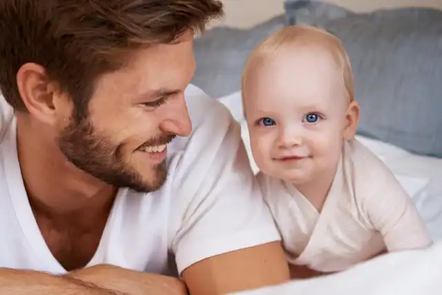Smiling father and baby lying on bed